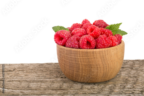 Raspberry in a wooden bowl on table with white background