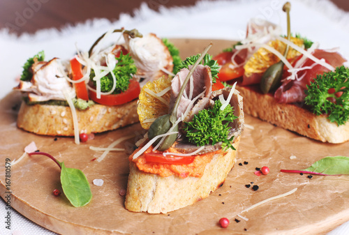 Bruschetta sandwich with ham, herbs and tomatoes on round board