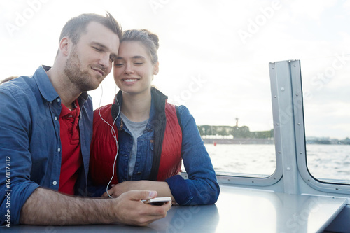 Restful couple listening to their favorite music during travel by steamer