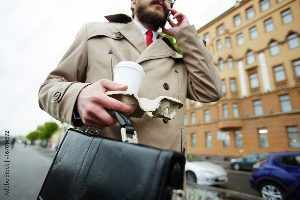 Busy salesman with briefcase and drink talking to client by cellphone foto  de Stock | Adobe Stock