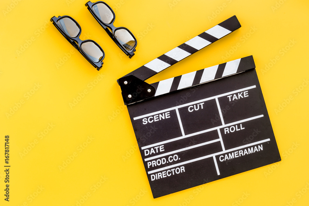 Filmmaker accessories. Clapperboard and glasses on yellow background top view copyspace