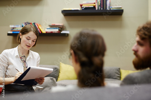 Fotografia Young counselor writing down story of married couple surviving hard times