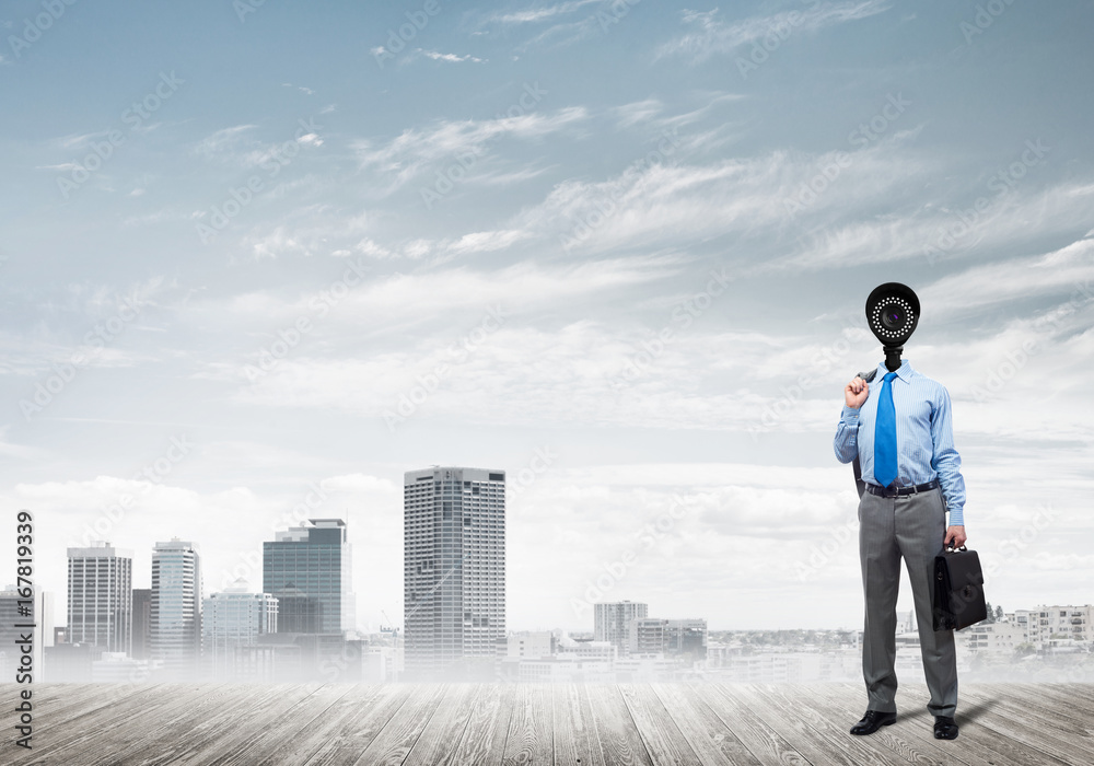 Camera headed man standing on wooden floor against modern cityscape Camera headed man standing on wooden floor against modern cityscape