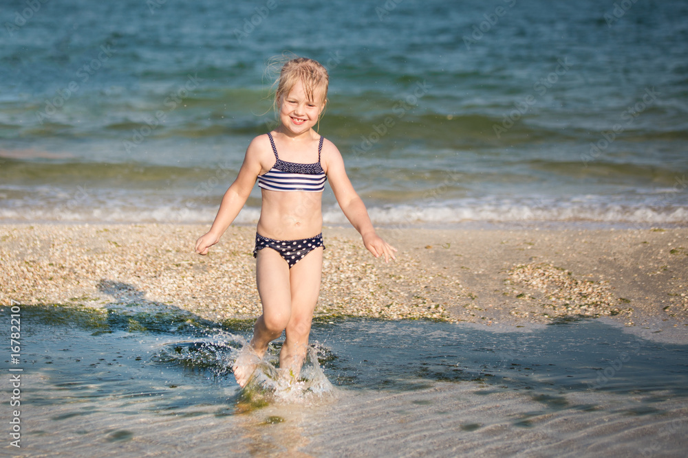 Little cute blonde girl running along the beach Little cute blonde girl running along the beach