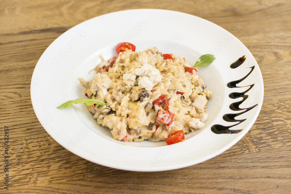 Fragrant Pilau/Pulav / pilaf /pilaf, fried rice with meat and vegetables on a white plate. Isolated on a wooden table. Fragrant Pilau/Pulav / pilaf /pilaf, fried rice with meat and vegetables on a white plate. Isolated on a wooden table.