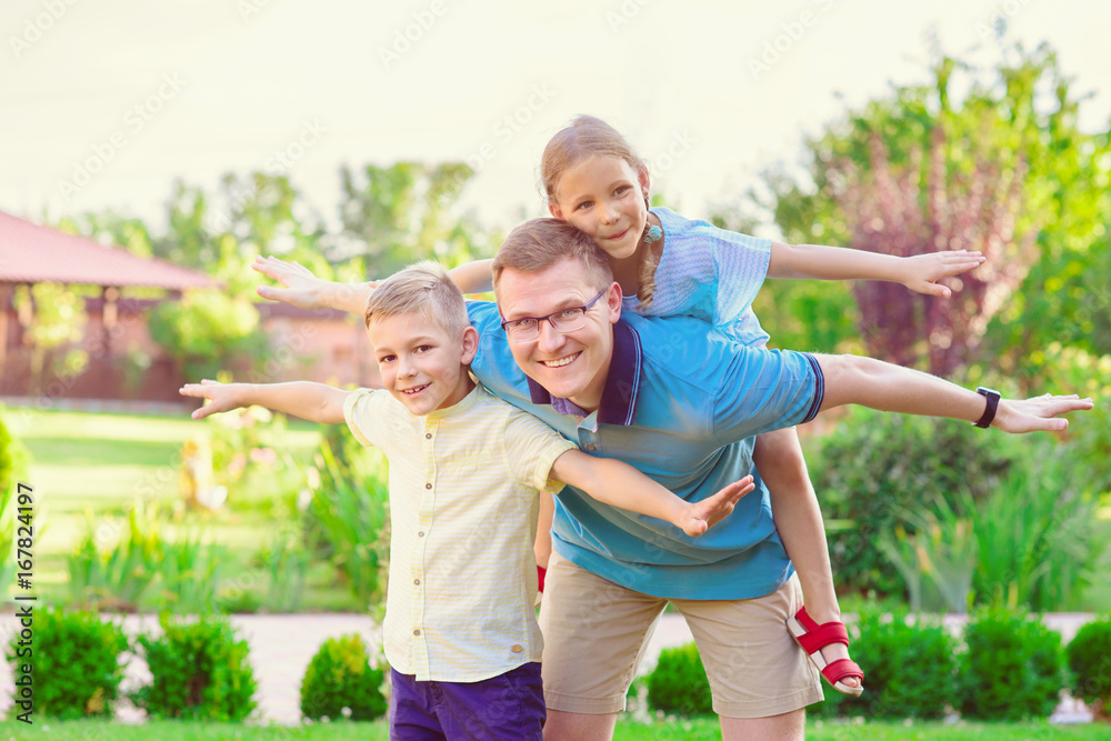 Fototapeta premium Portrait of happy father and two cute children playing at courtyard