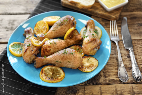 Delicious chicken legs with lemon on wooden table