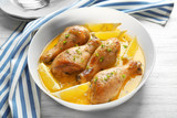 Delicious chicken legs with lemon in plate on wooden table