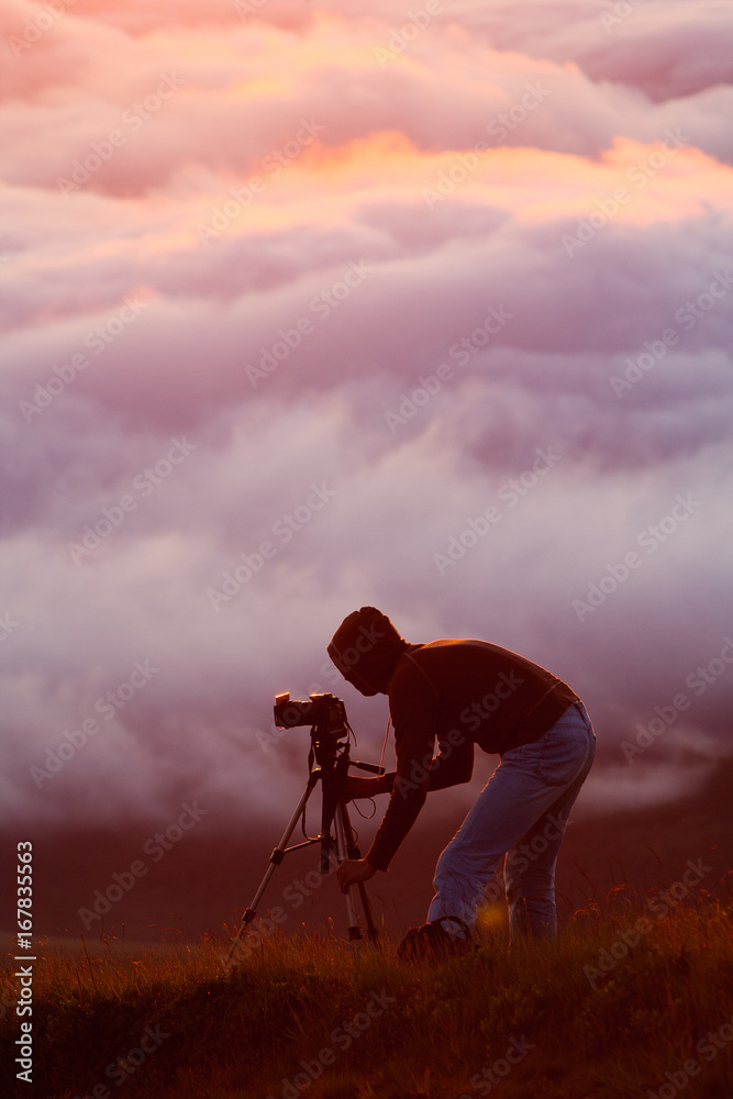 Naklejka premium Photographer shooting natural phenomenon - the clouds that roam the mountains. Concept theme: nature, weather, tourism, extreme, healthy lifestyle, adventures. Unrecognizable persones.