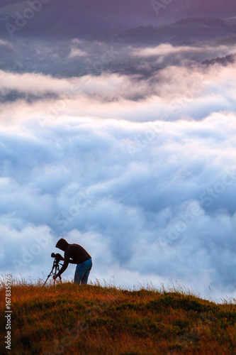 Photographer shooting natural phenomenon - the clouds that roam the mountains. Concept theme: nature, weather, tourism, extreme, healthy lifestyle, adventures. Unrecognizable persones. © Sodel Vladyslav
