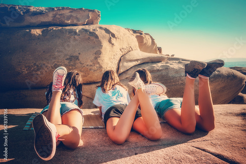 Back view of girls chilling out at the beach / Summer holidays / Teenage concept