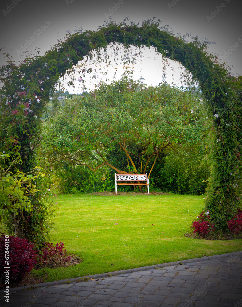 Φωτογραφία A wooden bench in the middle of a beautiful gardened park, surrounded by trees and grass, on a cloudy overcast day