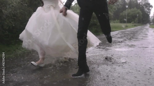 wedding in the rain. bride and the groom are under an umbrella.