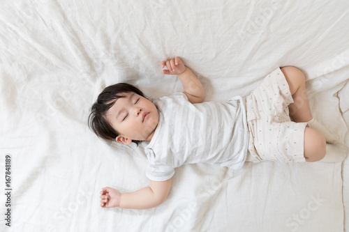 asian baby sleeping on bed