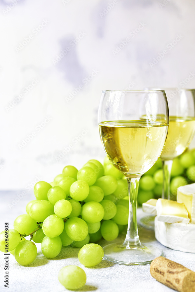 Two glasses of white wine,cheese and grapes. Two glasses of white wine,cheese and grapes.