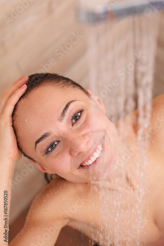 Young beautyful woman under shower in bathroom.