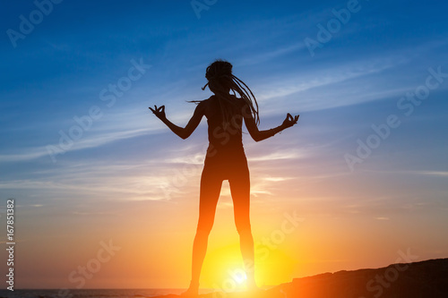 Silhouette of flexible dancing girl on the sea coast during a amazing sunset.