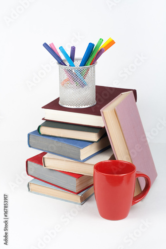 Open book, hardback colorful books on wooden table, white background. Back to school. Pens, pencils, cup. Copy space for text. Education business concept.