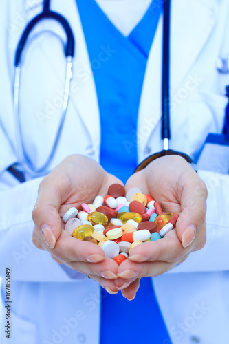 Doctor holding heap of drugs in a hand. Woman doctor