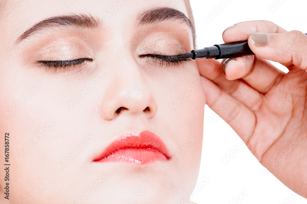 Stylist applying mascara on eyelashes with makeup brush to the beautiful woman