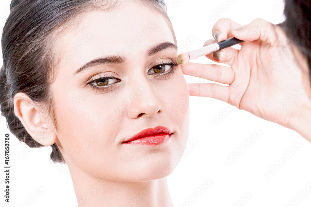 Stylist applying mascara on eyelashes with makeup brush to the beautiful woman