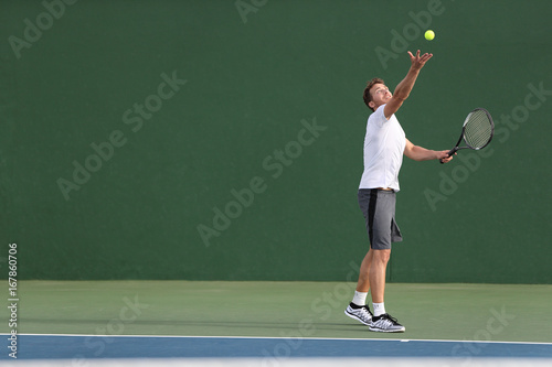 Tennis serve player man serving ball during match point on outdoor green court. Athlete playing sport game training doing exercise.