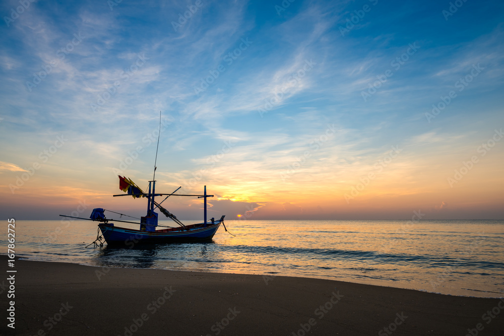 Sunrise on the sea beach with fishing boat