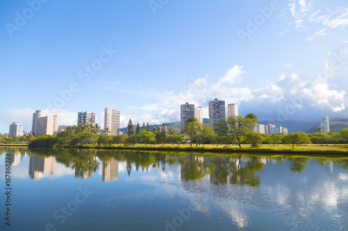 The picturesque panorama of Waikiki suburbs framed by the mirror-like canal surface  green golf course and distant mountains. The view of Ala Wai Canal in Waikiki resort area  Honolulu  Hawaii.