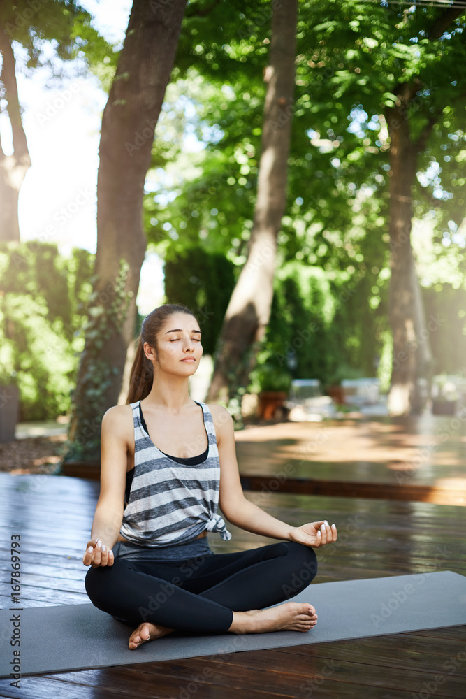 Young woman meditating in a yoga temple in the late afternoon trying to get her thoughts together. Young woman meditating in a yoga temple in the late afternoon trying to get her thoughts together.