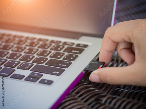 Closeup hand plugging memory card with laptop background.
