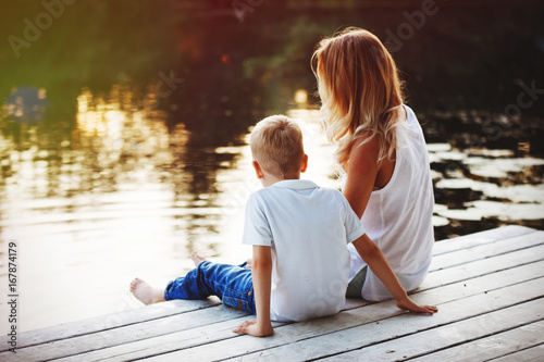 Family sitting near water and watching the lake at sunset