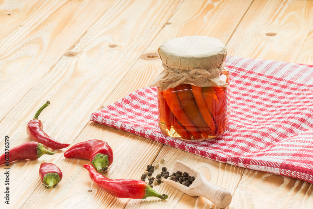 preserved chili pepper in glass jar on wooden table covered red squared napkin, jars, pepper, wooden scoop, copy space. free space for text preserved chili pepper in glass jar on wooden table covered red squared napkin, jars, pepper, wooden scoop, copy space. free space for text