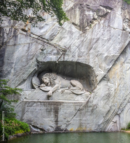 Dying lion monument (German: Lowendenkmal) carved on the face of stone cliff with the pond in the foreground in Luzern, Switzerland, Europe. photo