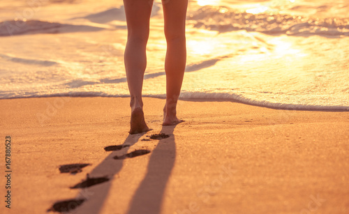 Woman walking down the beach at sunset. 