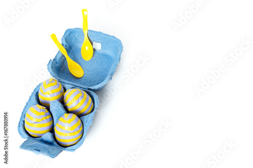 Foil covered chocolate easter eggs with plastic spoons in paper box on white background. Free copyspace for text. photo
