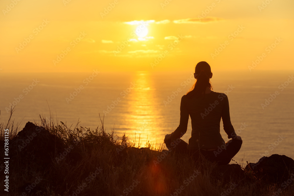 Young woman watching the beautiful sunrise. Peace and relaxation concept. 