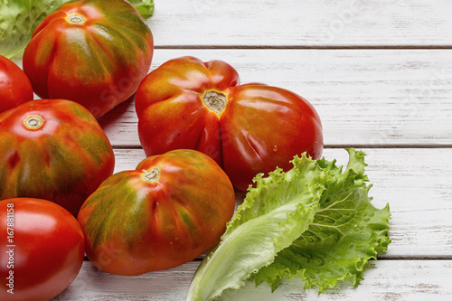 Fotografie Red tomatoes and salad on white wooden board