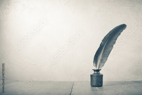 Foto Old quill pen with inkwell on wooden desk