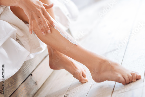 Close up of slim leg that being applied with cream