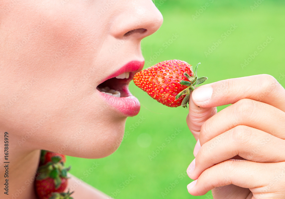 Beautiful woman eating fresh strawberries in the garden Beautiful woman eating fresh strawberries in the garden
