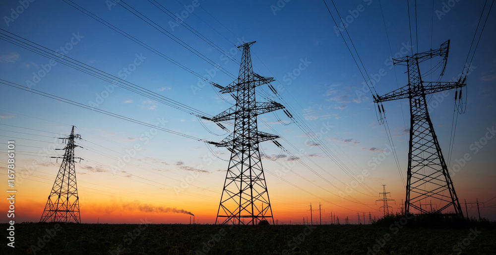 Silhouette of electricity pylons and high-voltage power lines on the field at sunset. Wire electrical energy at sunrise