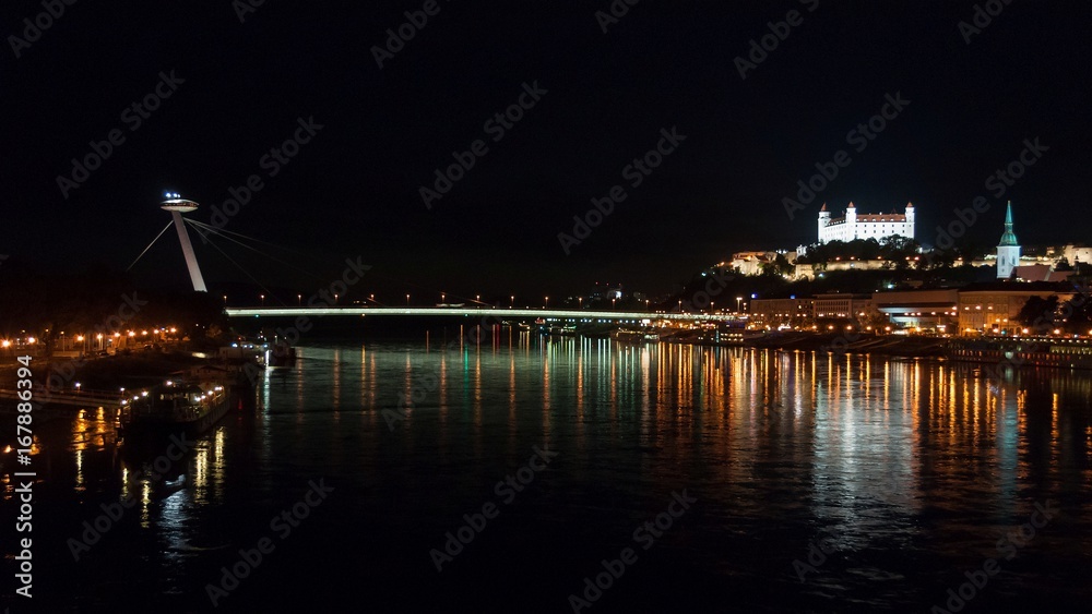 Night view of the lighted SNP bridge over Danube river and castle in capital city Bratislava, Slovakia