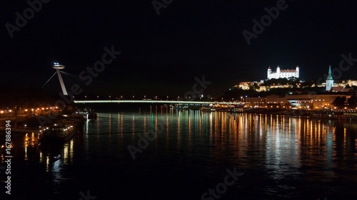 Night view of the lighted SNP bridge over Danube river and castle in capital city Bratislava, Slovakia