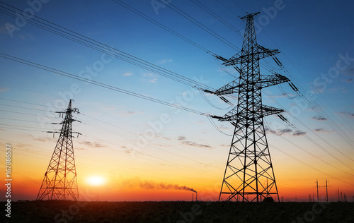 Silhouette of electricity pylons and high-voltage power lines on the field at sunset. Wire electrical energy at sunrise