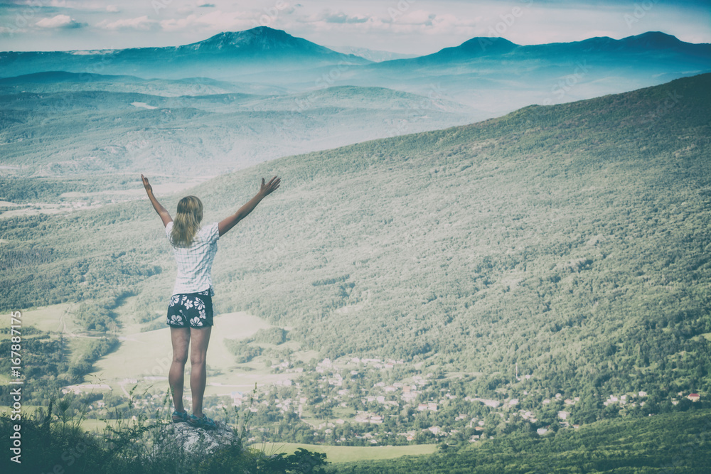 Happy woman standing on a cliffs edge. Instagram stylization