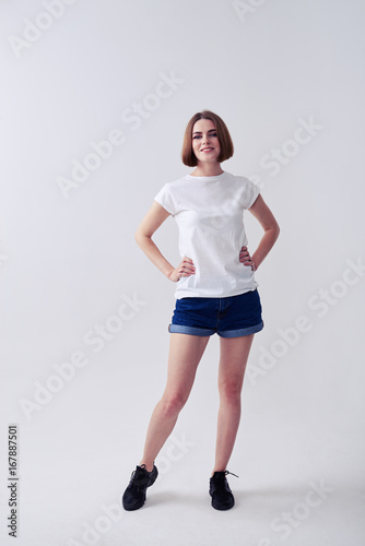 Pretty chestnut young woman posing in jeans shorts and white T-shirt
