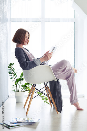 Pretty madam reading magazine on armchair photo