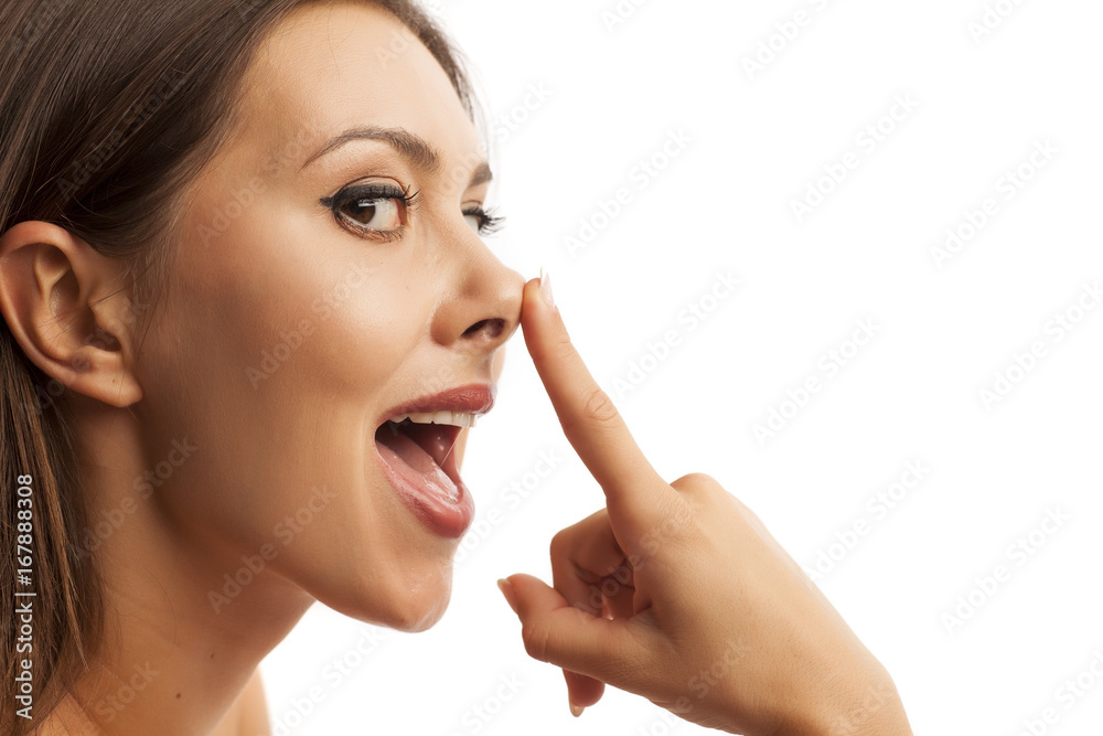 Beautiful smiling young woman touching her nose on white background Beautiful smiling young woman touching her nose on white background