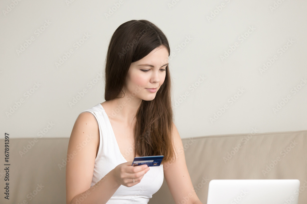 Young lady shopping on internet sitting at home with laptop computer, pretty girl paying for services by credit card, making secure online payment, purchases goods in web store, checking bank account Young lady shopping on internet sitting at home with laptop computer, pretty girl paying for services by credit card, making secure online payment, purchases goods in web store, checking bank account