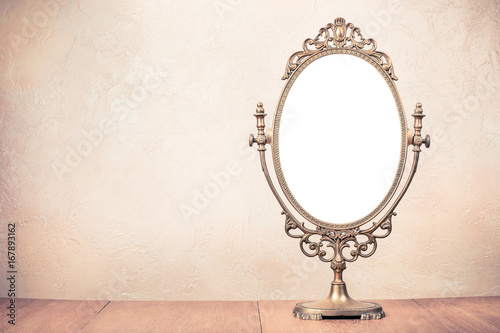 Old vintage bronze makeup mirror frame on table. Retro style filtered photo